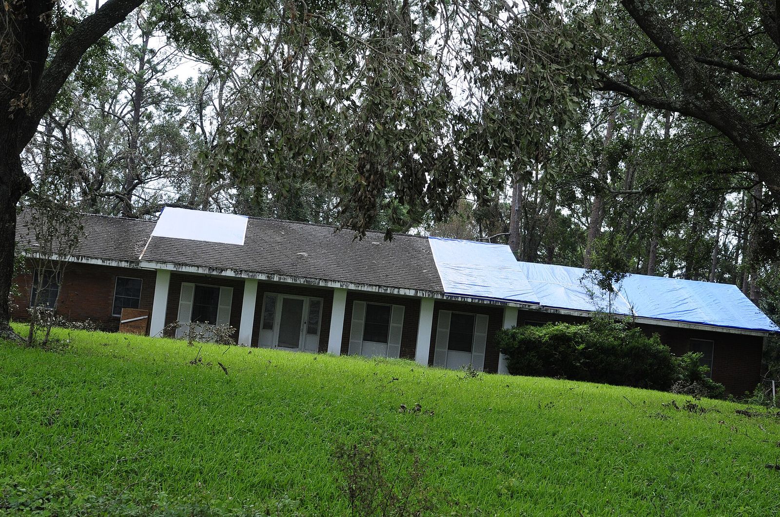House with a tarp on one roof slope the evening after a storm